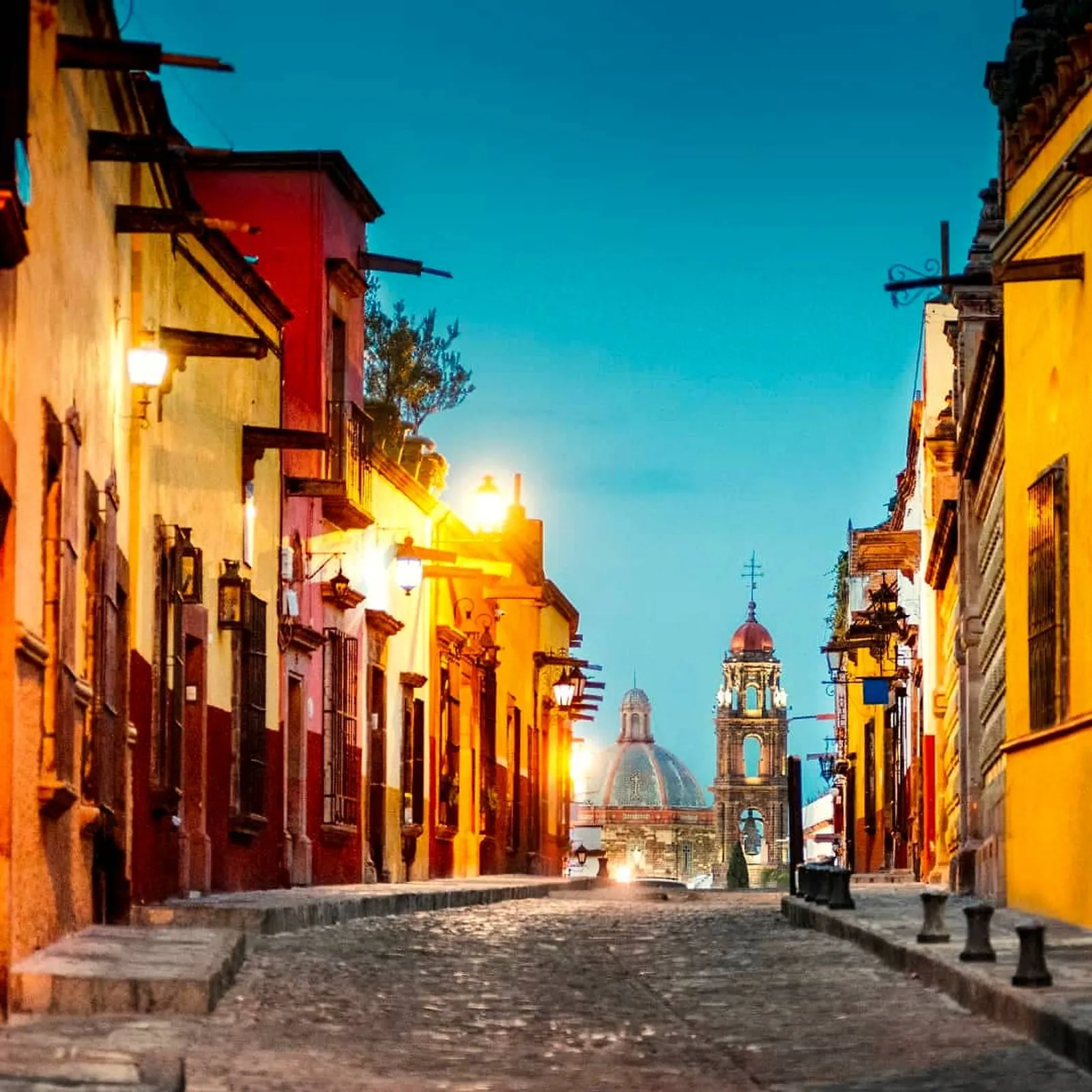 Scenic city tours Guanajuato along historic cobblestone streets Charming illuminated street with colorful colonial buildings during evening walking tours Guanajuato with church dome.